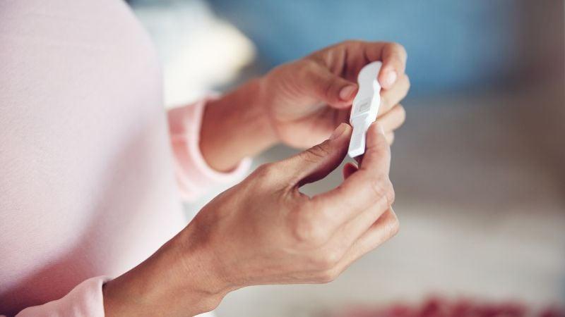 Woman looking at a positive pregnancy test