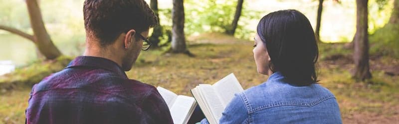 Couple struggling with infertility sitting on a bench reading a book Couple struggling with infertility sitting on a bench reading a book