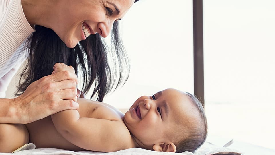 Moeder die haar kind over donorconceptie vertelt tijdens het verschonen van een luier Moeder die haar kind over donorconceptie vertelt tijdens het verschonen van een luier