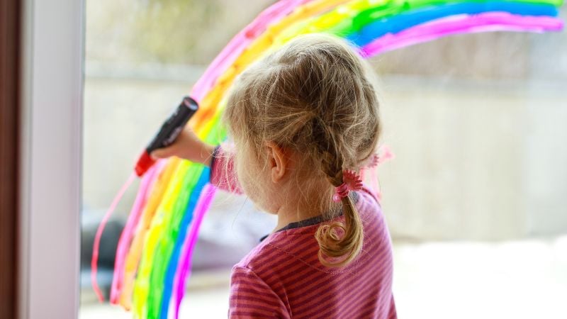 Ein Kind von LGBT+-Eltern malt einen Regenbogen