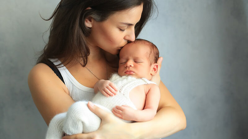 woman cuddling baby - single mother by choice (SMC) with her newborn - cryos international sperm and egg bank