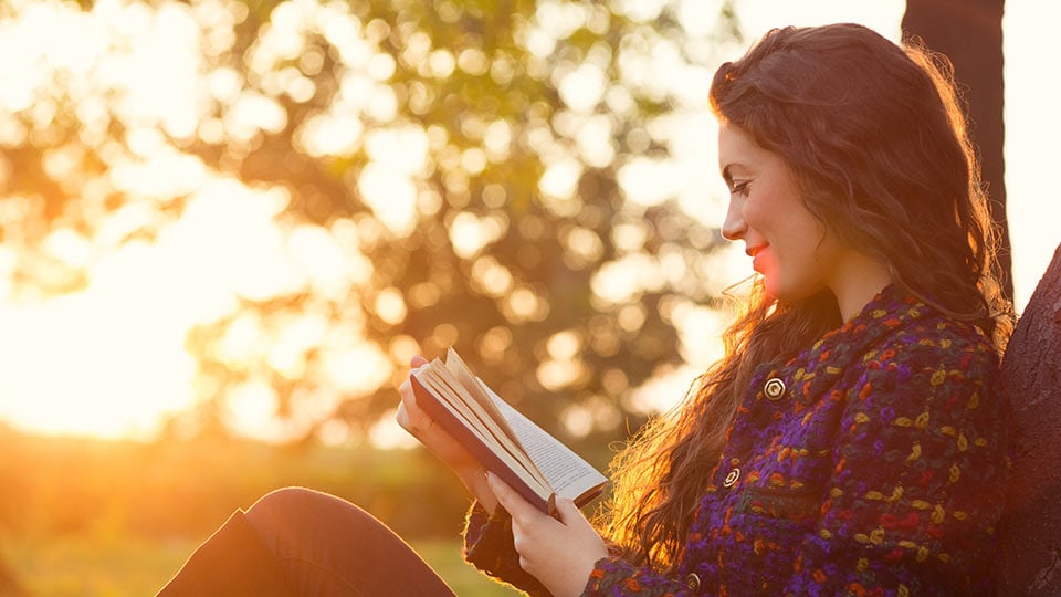 Young woman reading in the park – learn about Cryos’ egg donor profiles 