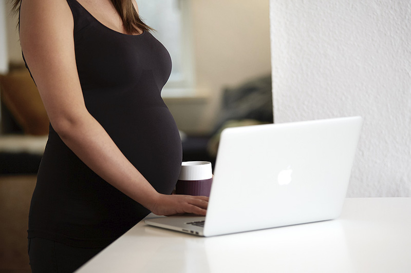 Pregnant woman reading a pregnancy guide to bodily changes online