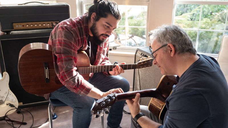 Sperm donor teaching another man to play guitar