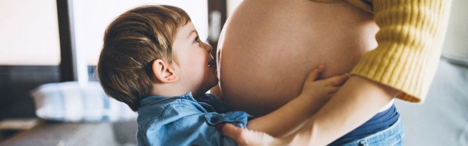 Un niño concebido con la ayuda de un donante de esperma besando la tripa de su madre embarazada