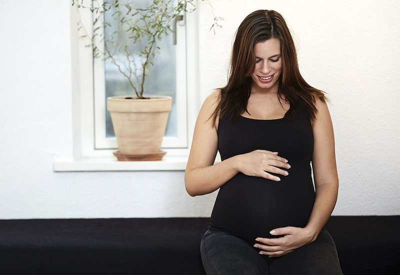 妊娠中の身体を見つめる女性
