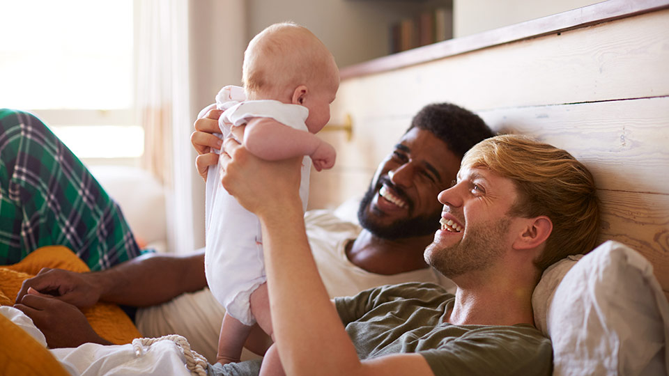 Happy gay couple with their baby daughter. Use an egg donor and a surrogate to have a baby as a homosexual couple 