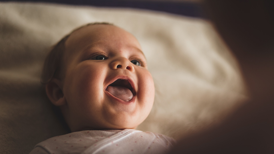 Schattige baby glimlacht naar haar ouder na zwangerschap met donoreicellen