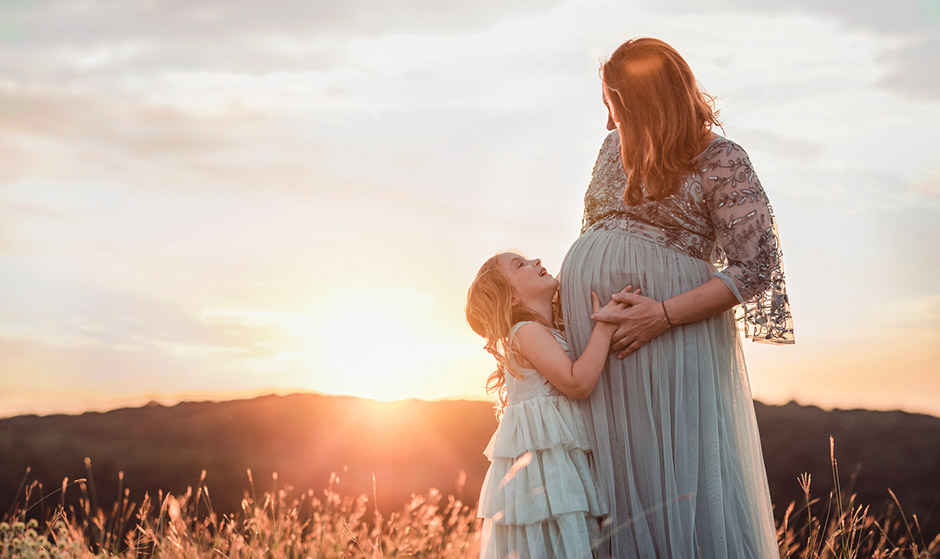 Daughter hugging mother who is pregnant after fertility treatment with ...