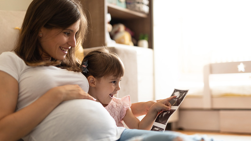Mutter und Kind betrachten Bild eines künftigen Geschwisterchens – reservieren Sie Spendereizellen für Geschwisterkinder