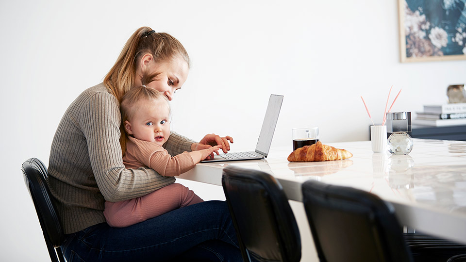 Mutter mit Kind und Laptop fragt Versand und Lieferung von Spendereizellen für eine Kinderwunschbehandlung an
