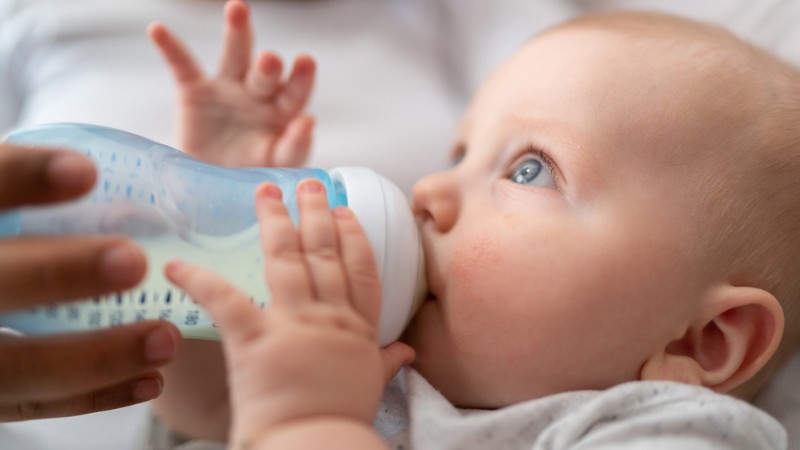 Un bebé tomando leche de fórmula en biberón