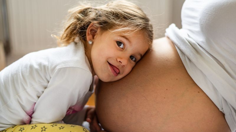 Happy donor-conceived child with her head on her mothers belly