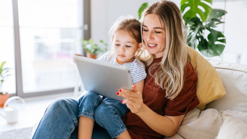 Single mother and her child playing on an Ipad Single mother and her child playing on an Ipad