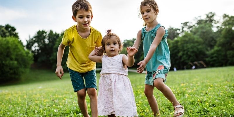 Three donor-conceived children playing in grass