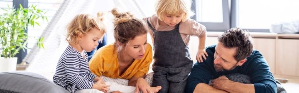 En glad familie med donorbørn der læser en bog