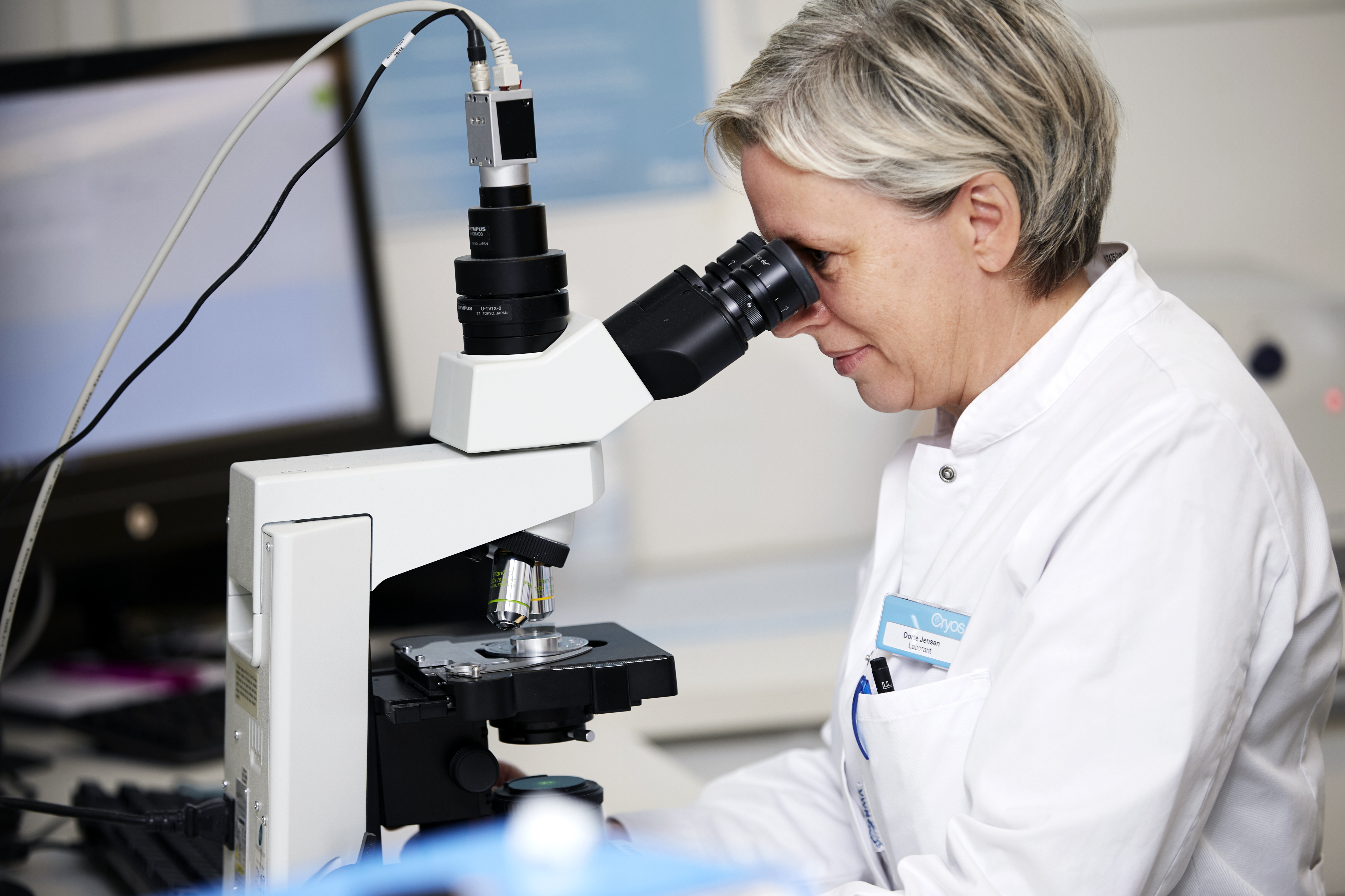 Woman lab technician looking at sperm cells through a microscope – Photo from the Cryos press kit. 